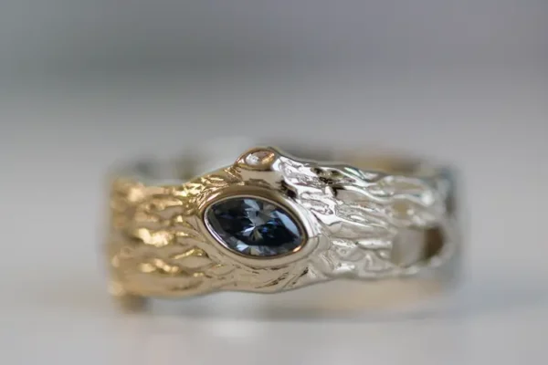 A tree-log textured ring with a blue memorial diamond in the middle