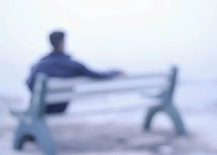 Blurry picture of a man sitting on a bench