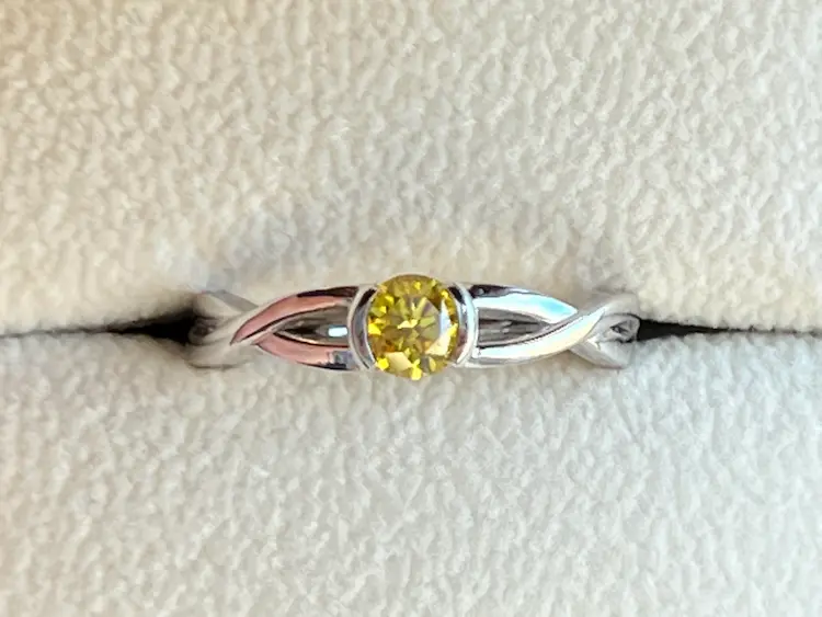 A infinity ring setting with a yellow memorial diamond in the middle