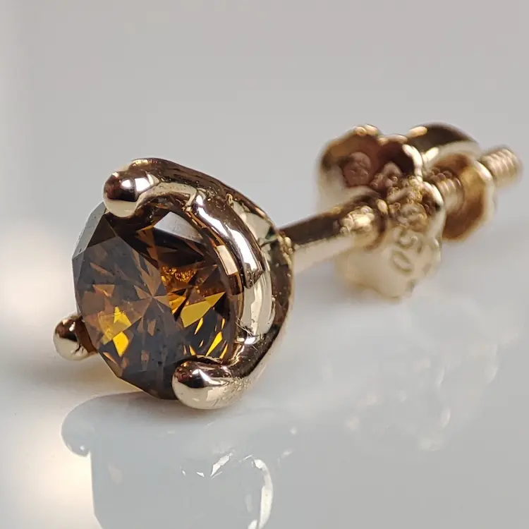 A amber colored memorial diamond set in an earring