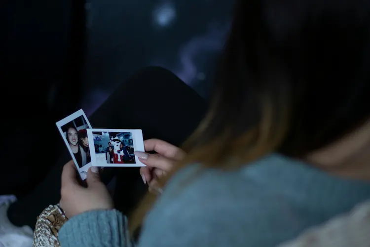 A woman looking at Polaroid pictures.