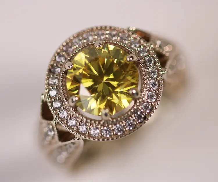 A yellow round cut memorial diamond in a vintage ring.