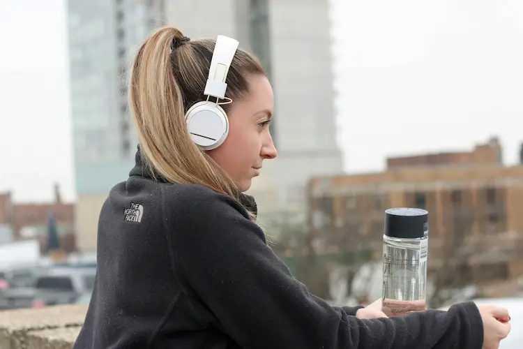 A woman, listening to music on headphones, looking over a city