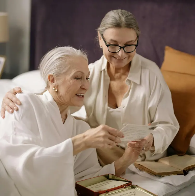 A woman and an older woman, reading a letter.