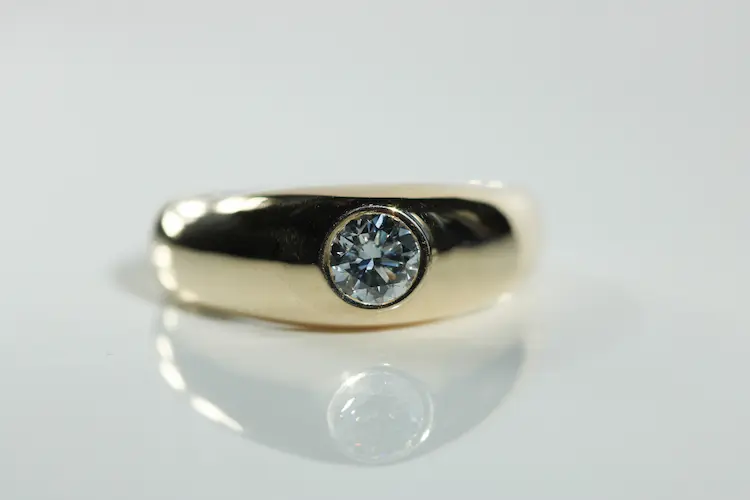 A yellow gold wedding band with a blue memorial diamond.