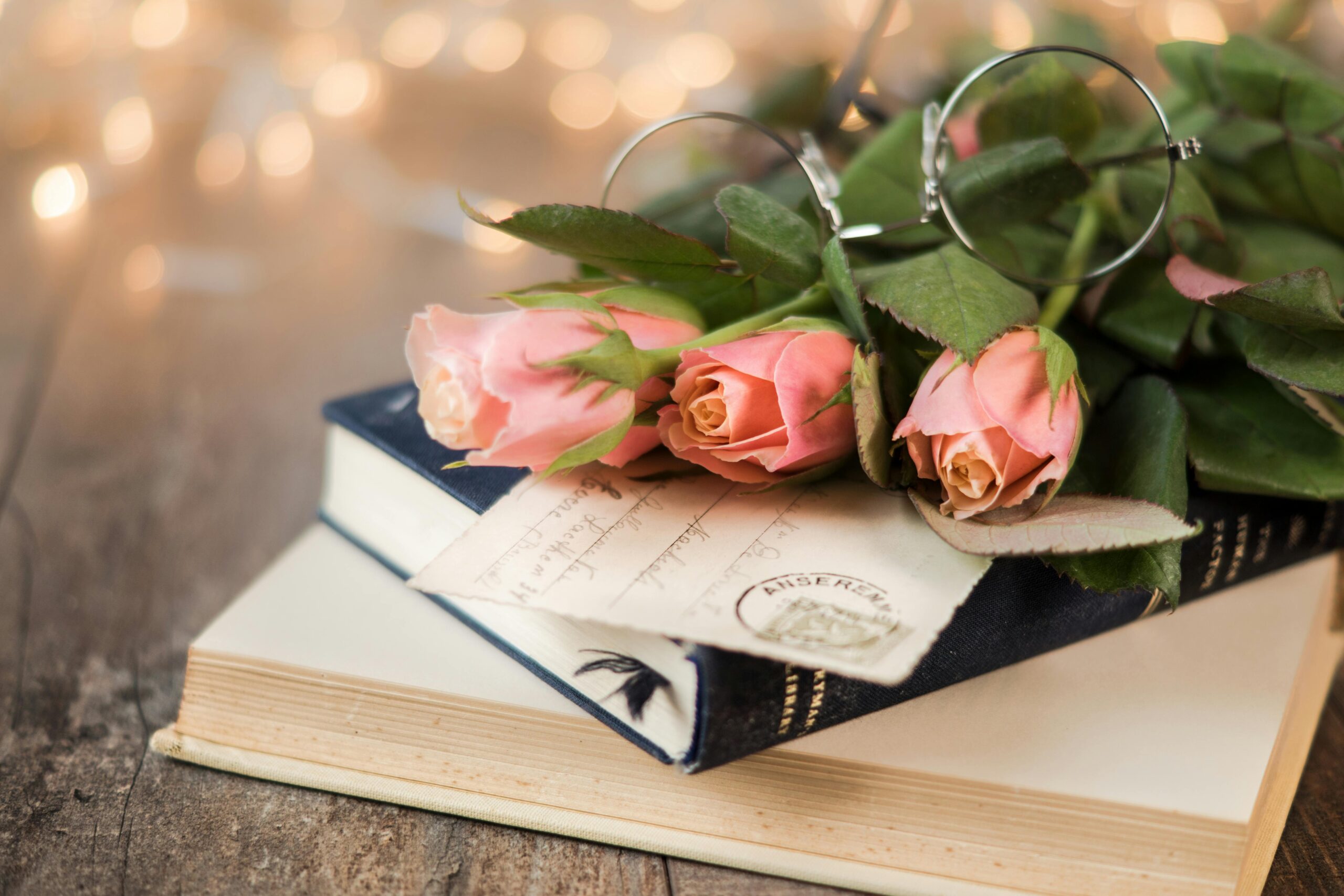 A card and pink roses on top of two books.