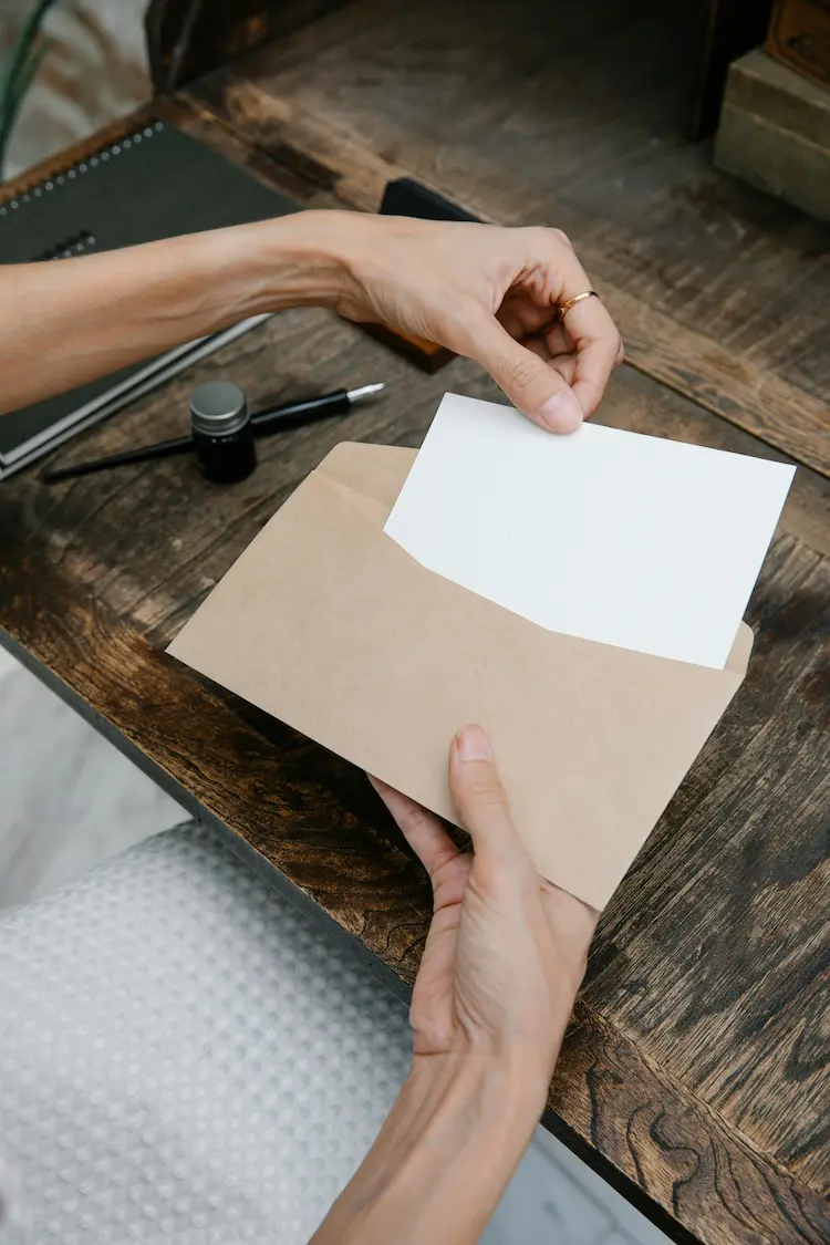 A person, taking out a blank piece of paper out of an envelope.