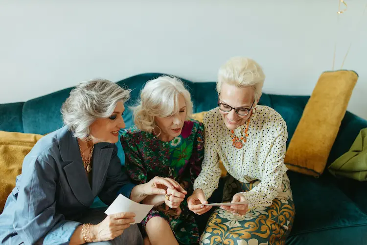 3 middle-aged women, looking over pictures.